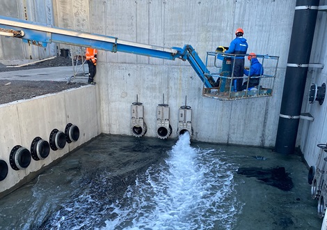 Workers in a crane above a tank and knife gate valves